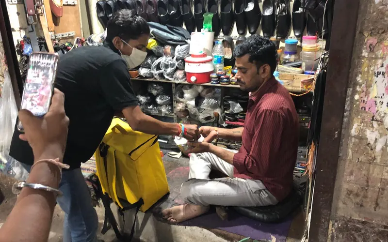 Sewan staff handing a meal to a shopkeeper in a shoe shop