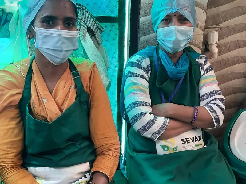 Two Sewan canteen workers in green aprons